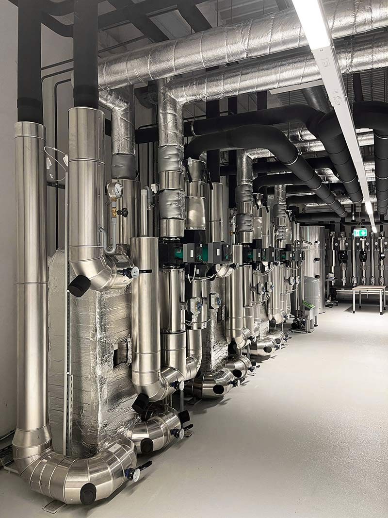 Gedämmte Rohrleitungen mit Pumpen und Armaturen in einer Technikzentrale